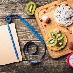 planning-healthy-diet-concept-workout-fitness-dieting-fruits-toasts-measuring-tape-empty-notebook-wooden-table-slimming-plan-with-fruits-top-view-copy-space